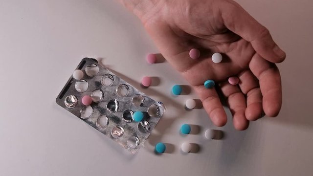 Man's Hand And Chaotically Scattered Tablets. The Light Flashes Blue Like An Ambulance Siren. The Concept Of The Dangers Of Drugs And Narcotic Substances, Overdose And Suicide, Crime And Drug Business