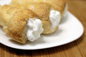 Rolls of puff pastry with protein cream on a white plate. Homemade sweet pastries for dessert