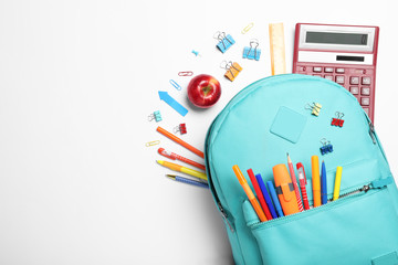 Stylish backpack with different school stationery on white background, top view