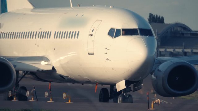Airplane taxiing from the taxiway to runway for taking off at sunset