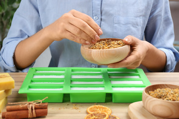 Woman making natural handmade soap at wooden table, closeup