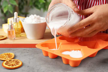 Woman making natural handmade soap at grey stone table, closeup