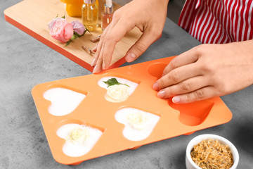 Woman making natural handmade soap at grey stone table, closeup