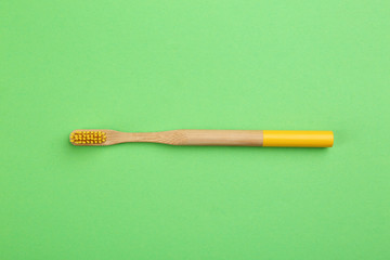 Natural bamboo toothbrush on green background, top view