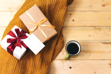 coffee cup and gift box, empty card above woolen scarf on wooden table  hello winter and christmas concept