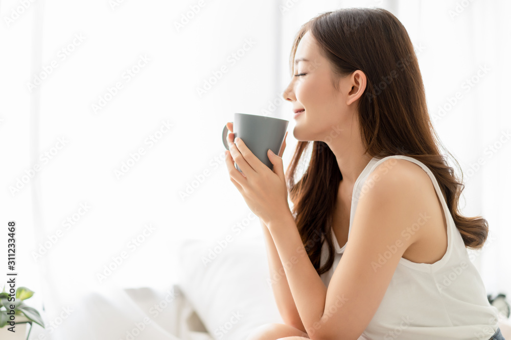 Wall mural happy smiling beautiful asian woman enjoying first morning and smelling aroma of cup of coffee tea i