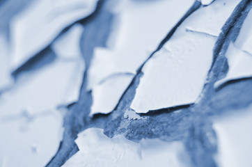 Light blue painted old exterior wall closeup with cracked, scratched and peeling paint, abstract abandoned backdrop, blue flaking paint texture