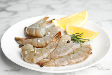 Fresh raw shrimps with lemon and rosemary on marble table