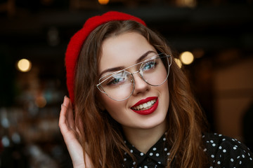 Happy smiling woman wearing glasses, red beret, polka dot blouse looking at camera. Natural light. Copy, empty space for text