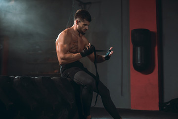 Details closeup bodybuilding concept guy wraps his hands with a professional bandages preparing for training in the gym class
