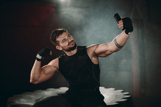 A muscular man takes pictures with his phone after a heavy exercise