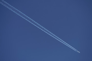 Flugzeug in großer Höhe mit Kondenstreifen und blauer Himmel - Stockfoto
