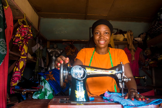 portrait of a young african female tailor smiling while working with her sewing machine