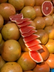 a close up shot on intact and sliced grapefruit in an open market booth