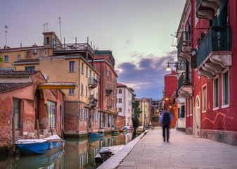 twinlights, Empty Venice street with scenic ancient buildings,  traditional boats on a water canal, moving people silhouette on empty street - 311239005