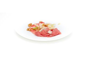 albese meat with savoy cabbage, walnuts, celery and parmesan cheese in the foreground on plate and white background
