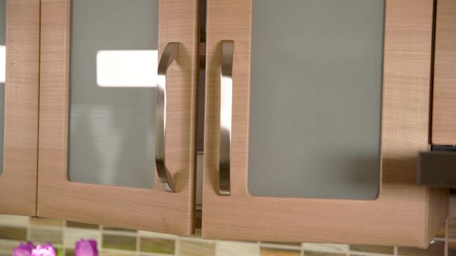 woman pulls mug out of the kitchen cupboard and closes the cabinet door