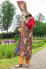 A man standing in mask and masquerade costume in Annevoie  gardens, Belgium - 311239247