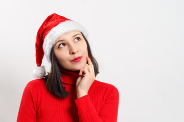 sweet dreamy young woman in a red sweater and Christmas hat. on white