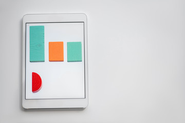 Colorful chart made up of flat wooden bricks lying in row on screen of tablet