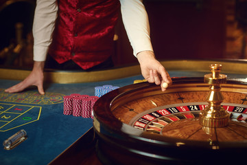 Croupier holds a roulette ball in a casino in his hand