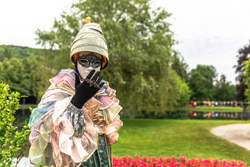 A man standing in mask and masquerade costume agains the park background - 311239886