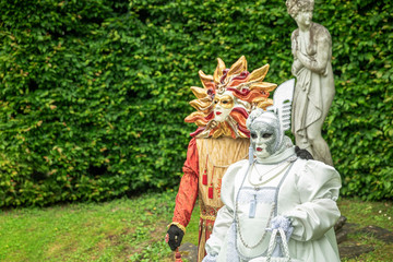 Fototapeta na wymiar Couple standing in masks and masquerade costumes during Venetian carnival in Annevoie gardens, Rue des jardins, 37 a, Annevoie/ Belgium