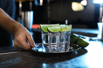 Bartender with shot glasses of Mexican Tequila at bar counter, closeup