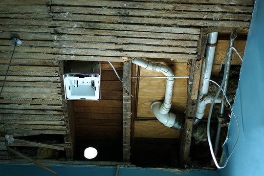 Open Old Wood Ceiling With Water Pipes And Installed Fan.