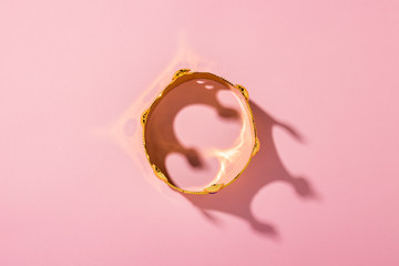 Gold crown on a pink background. Flat lay, top view