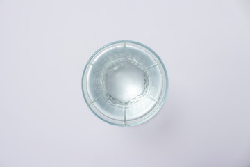 Glass with pure crystal water on a white background under sunlight. Banner. Concept of thirst, heat, summer, tropic. Flat lay, top view