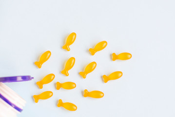 Omega vitamins for children in the form of fish on a blue background. Useful supplements for children.