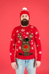 still believe in santa claus. mature bearded man reindeer sweater. brutal hipster in knitted hat red background. wear christmas mood. knitwear male fashion. funny looking man. new year party