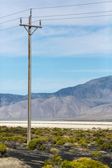 Obraz premium Power lines pole against a blue sky next to the black rock desert nevada
