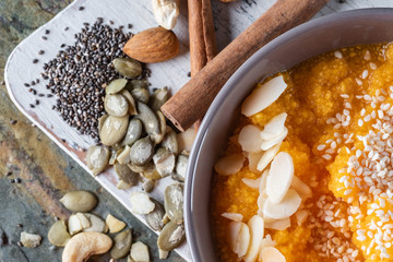 Pumpkin porridge with seeds on wooden table with chia and almond seeds