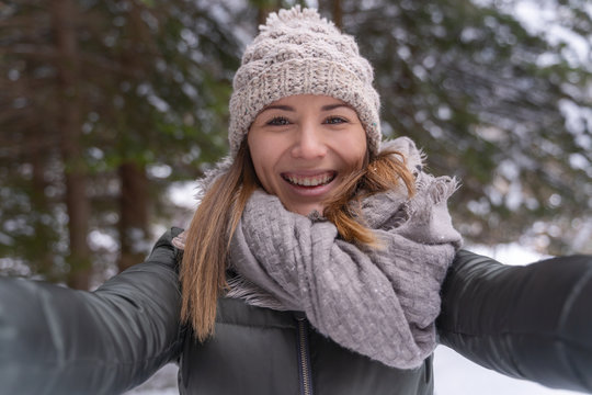 young woman taking a self portrait picture and smiling in the nature during winter season
