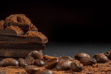 Coffee beans with broken chocolate slices close-up on a dark background