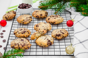 Traditional american cookies with chocolate chips on a metal wire rack on a white wooden background. Festive dessert for the New Year and Christmas. Close up.