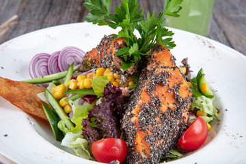 A fresh grilled salmon stake on a plate with tomatoes and salad. Grilled Salmon salad and chia seeds.