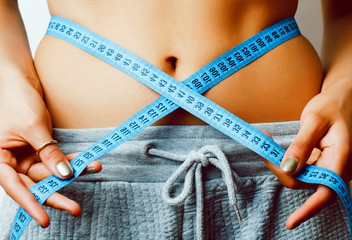 woman measuring waist with tape on knot like a gift closeup on white background