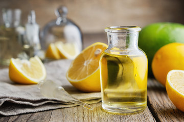 Bottle of citrus lemon essential oil and citrus fruits on table.