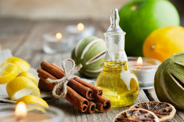 Bottle of citrus lemon essential oil for aromatherapy, citrus fruits, cinnamon sticks and burning...