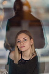 Young blond hair woman looking trough the window. Silhouette in window. Concept. Vertical.