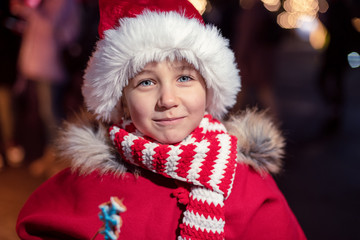 Child on christmas market. cute lovely girl in red hat standing at street happy about gingerbread cookies. Traditional leisure for families on xmas holidays. Family, tradition, holiday concept