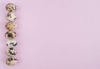 Easter flat lay with quail eggs in a row on pink  background.  Top view, copy space. 