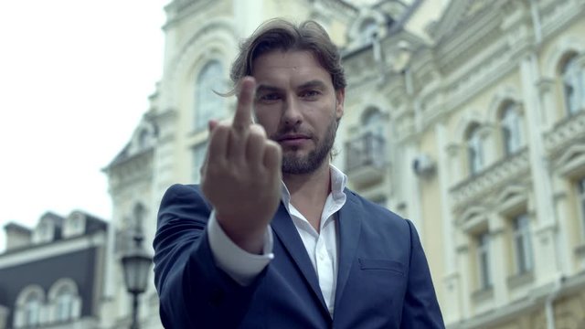 Young businessman in suit showing fuck sign in the street