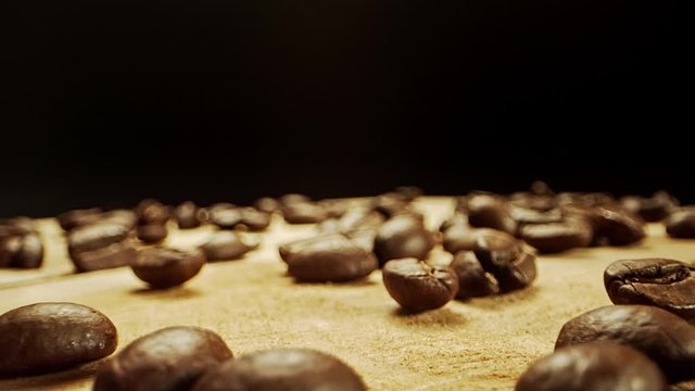 Close camera movement through fresh coffee beans laying on a wooden surface