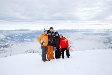 Happy family on ski resort vacation on the mountain hillside, having fun outdoors on mountain skyline in winter. Travel background with mountains. Snow, sport, ski, recreation.