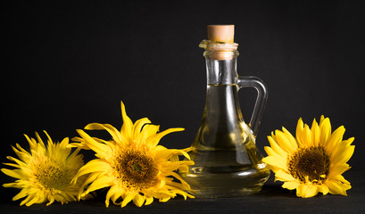 .bottle of oil and sunflowers on a black background