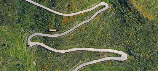 Aerial drone ultra wide photo of snake road crossing hill in Mediterranean destination